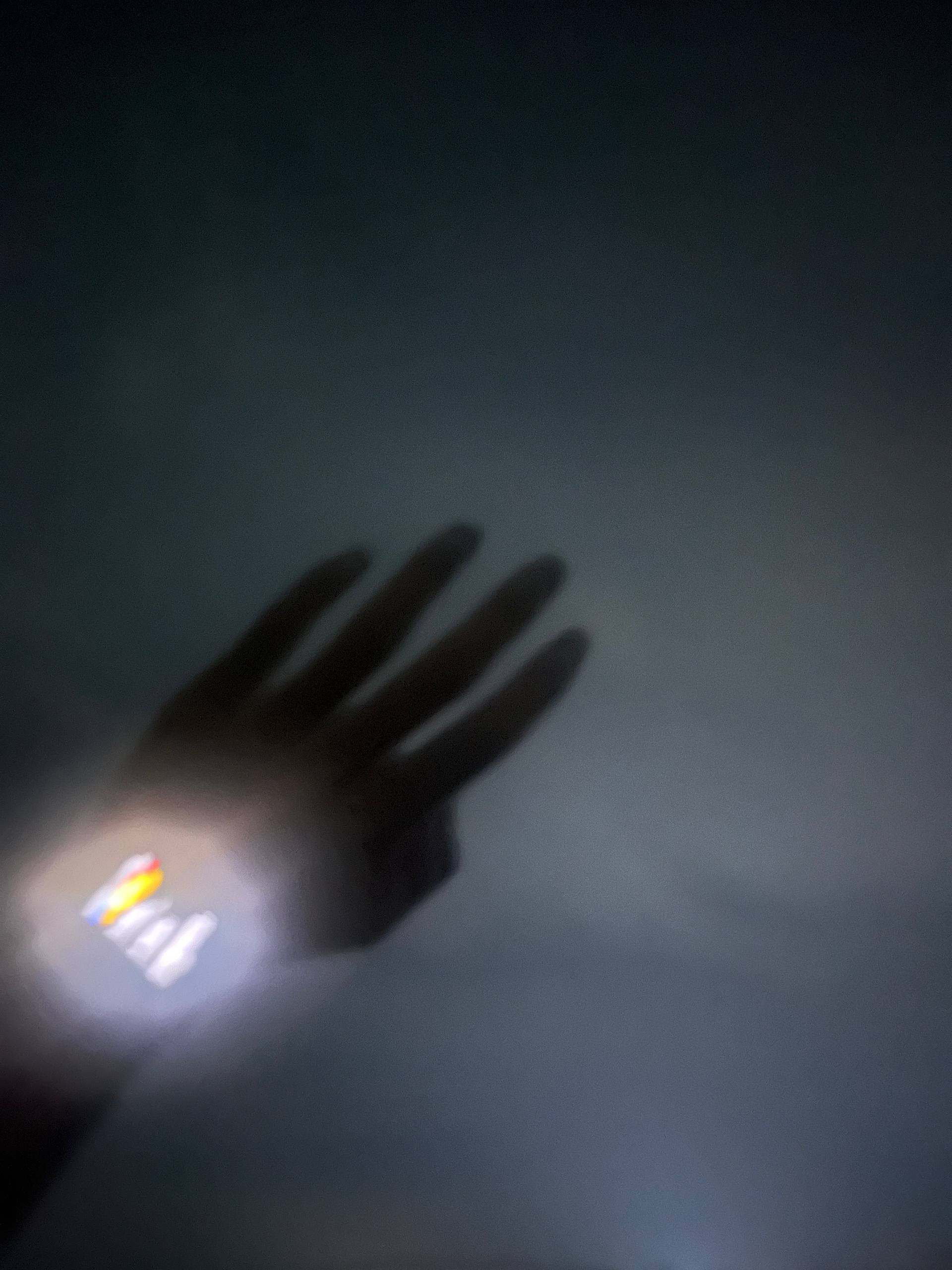 A blurred hand and wristwatch moving across a dark gray background.