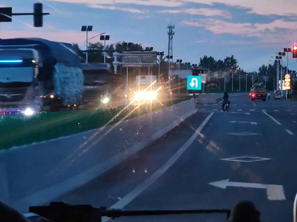 A view from inside a bus or vehicle on a road at dusk.